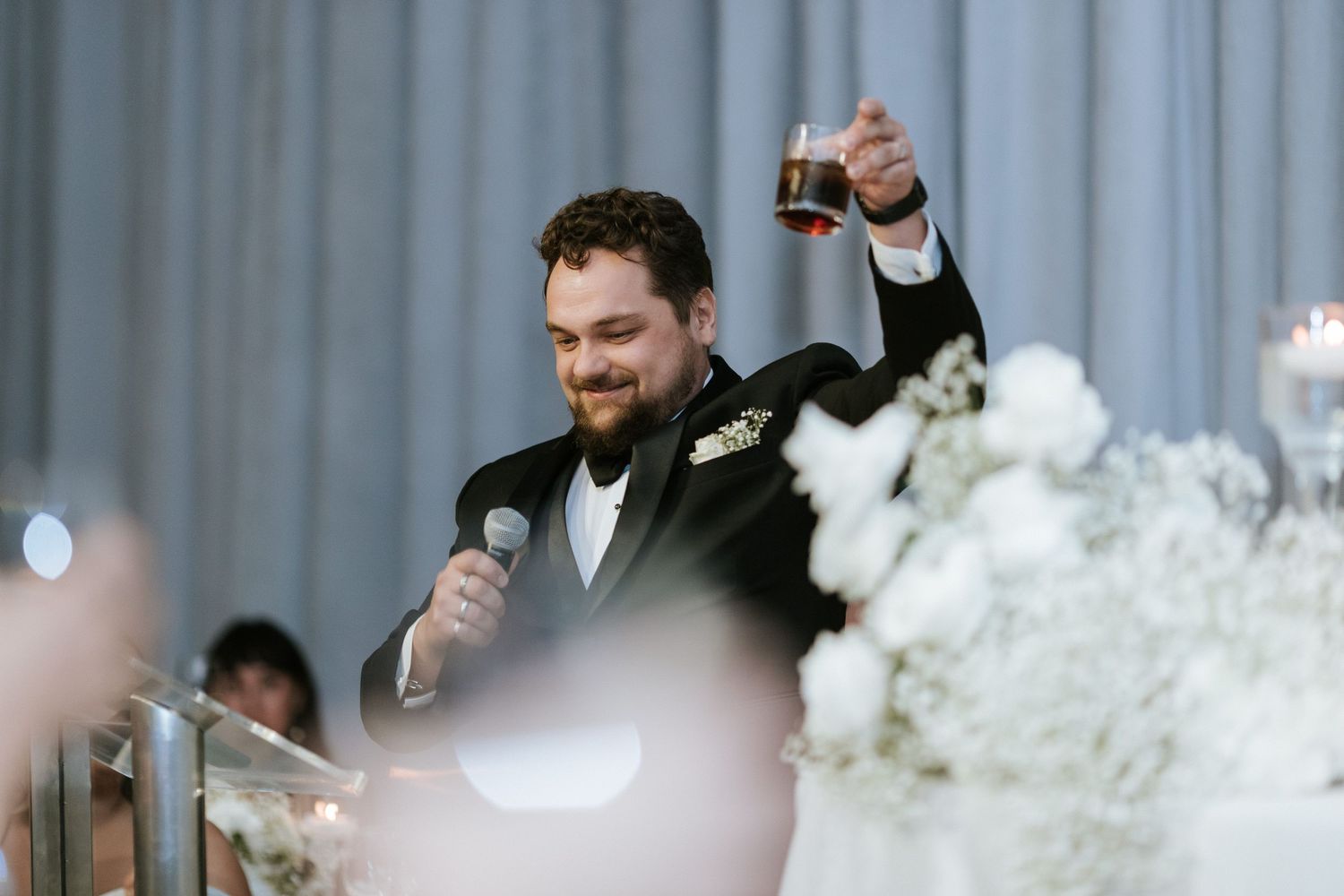 Wedding guest raises glass during celebratory toast at elegant reception.