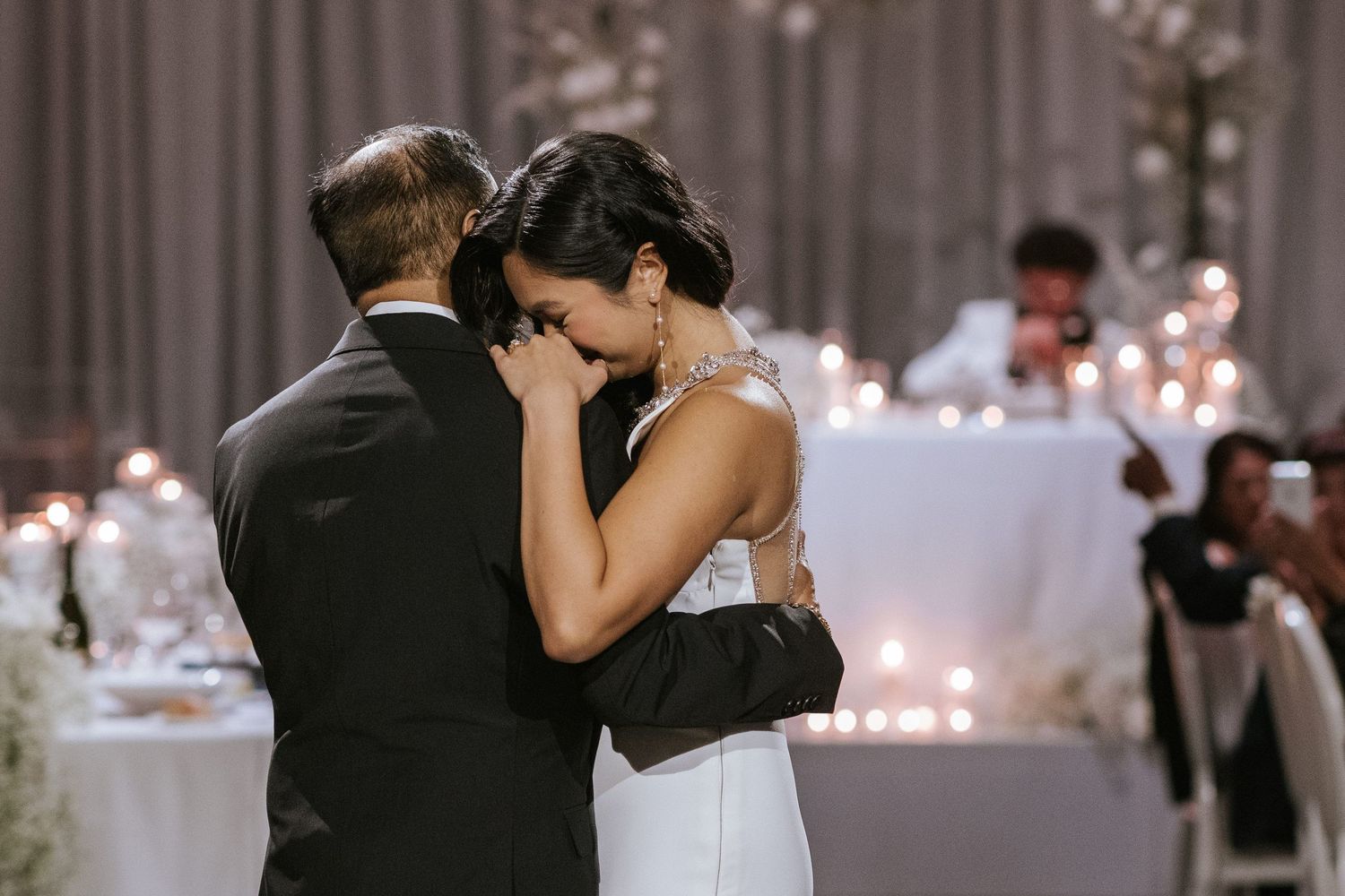 Intimate dance moment between couple at elegant wedding reception with soft lighting.