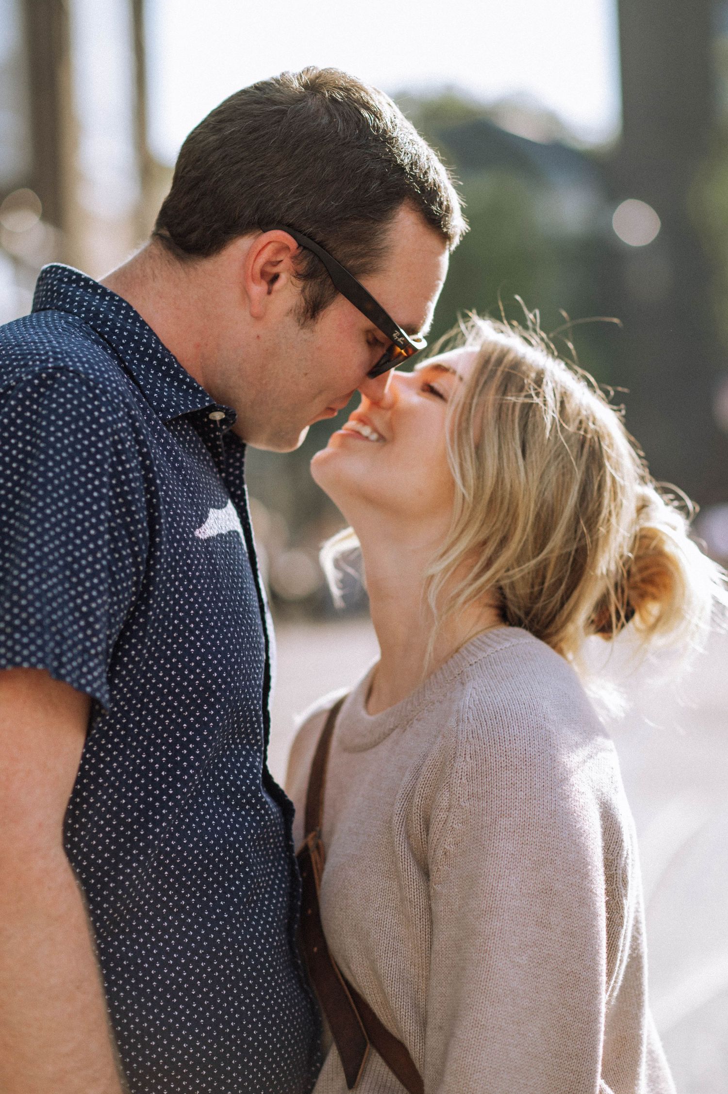 Romantic couple sharing an intimate moment in sunlit outdoor setting.