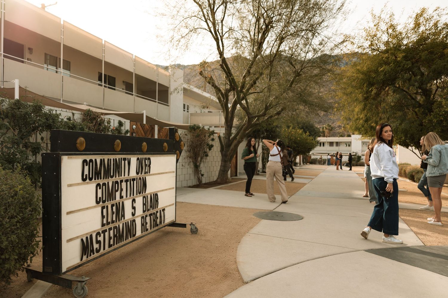 A vintage-style street view with a sign and photographers walking past.