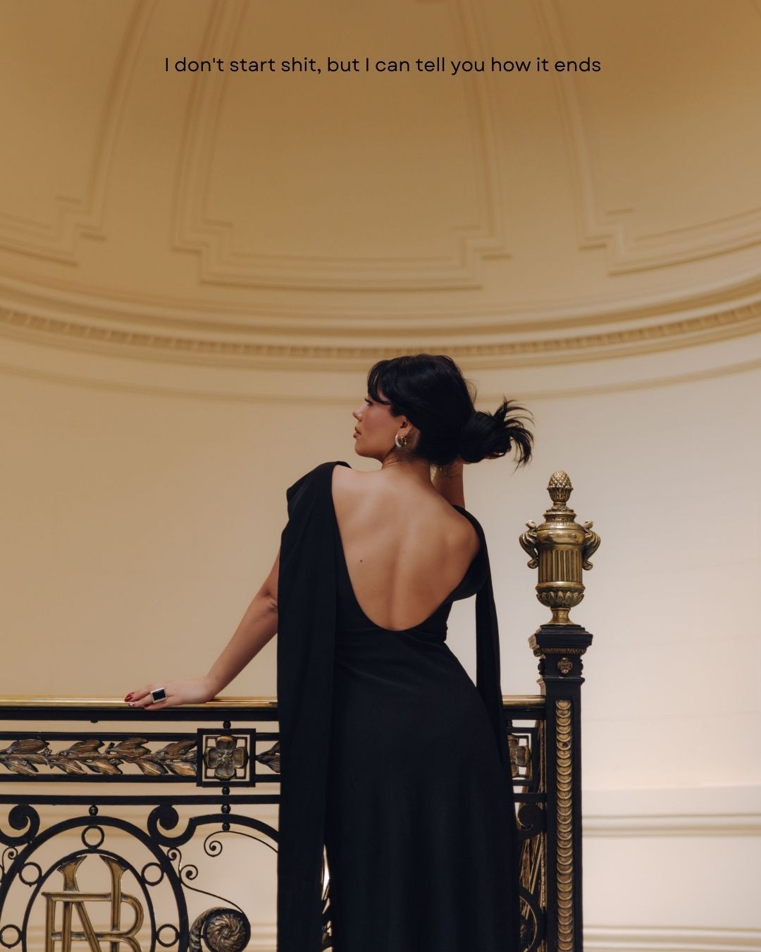 Woman in a backless black gown standing on an ornate balcony with a bold quote overlay.