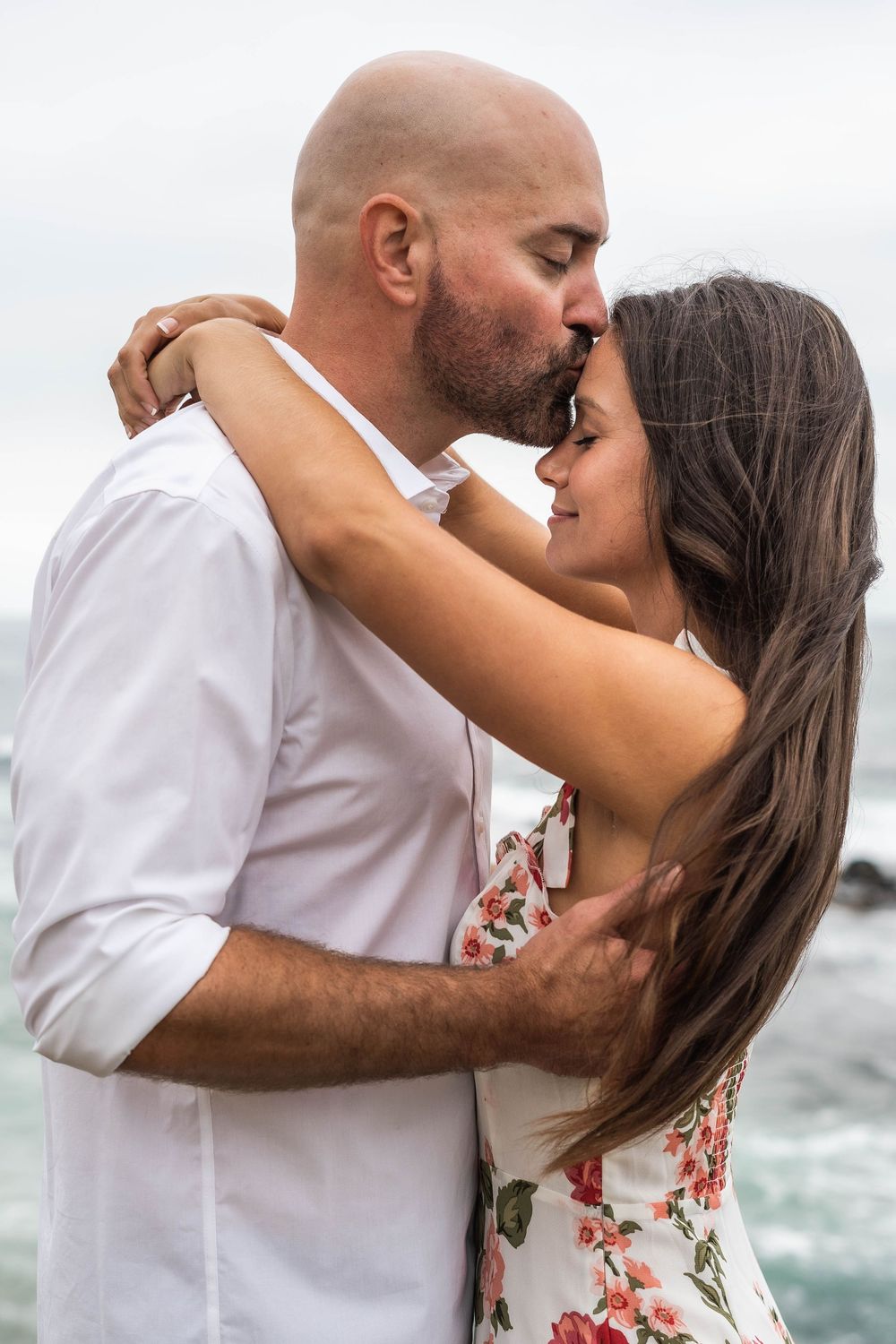 A couple embraces passionately on a beach in a series of romantic photos with crashing waves in the background.