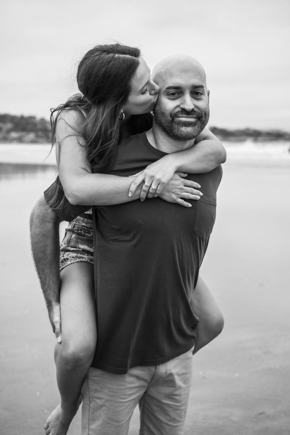 A series of black and white photos showing a couple embracing and laughing together on a beach.
