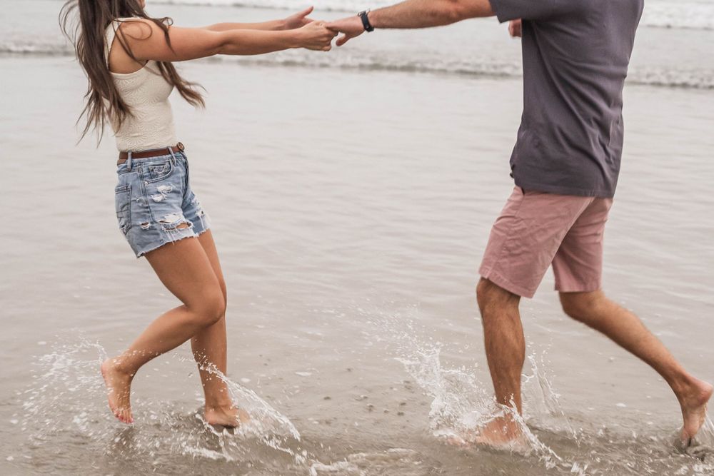 Two people splashing and playing in the ocean waves at the beach.
