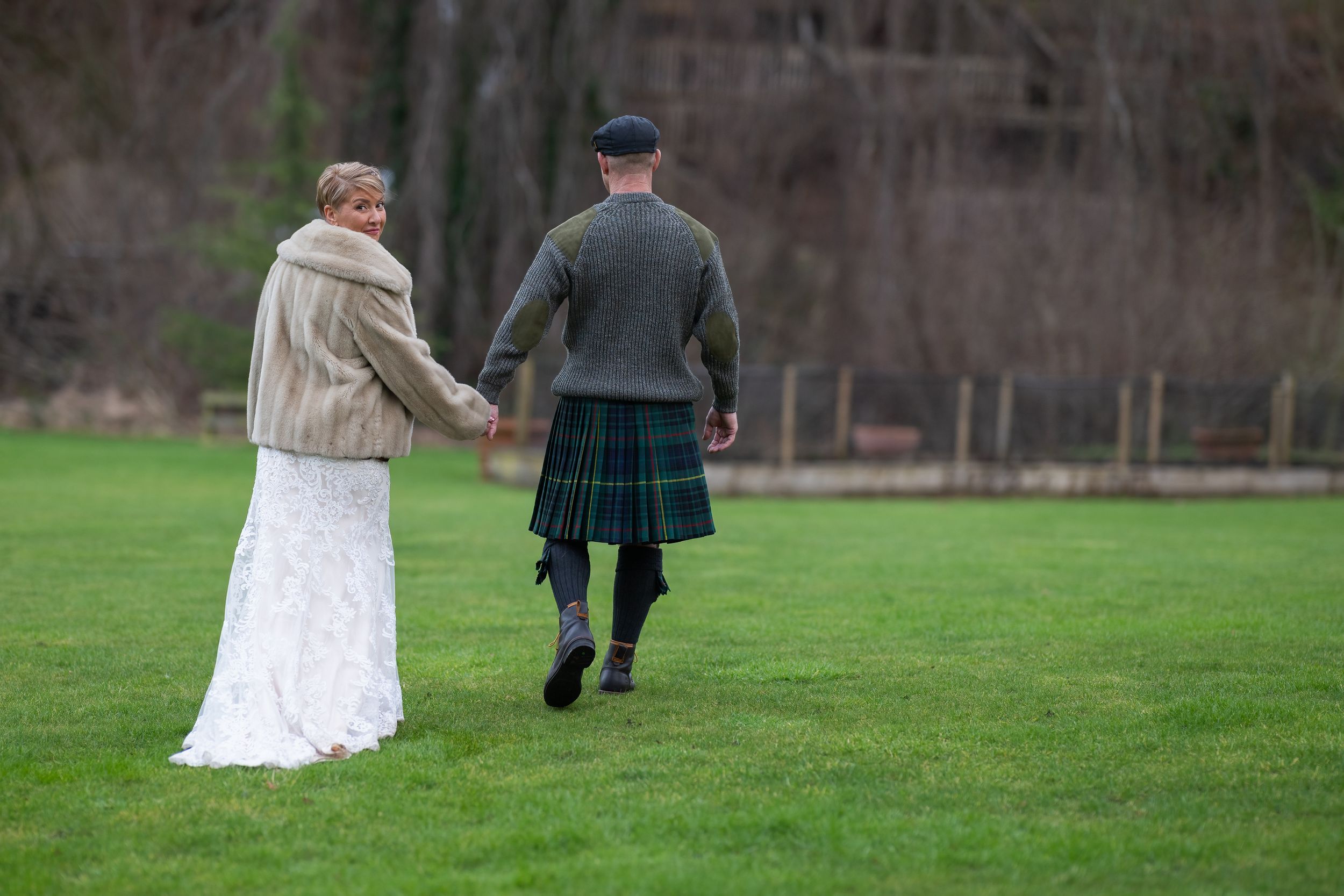 Bride and groom walking on grass at dalkeith country park, Edinburgh