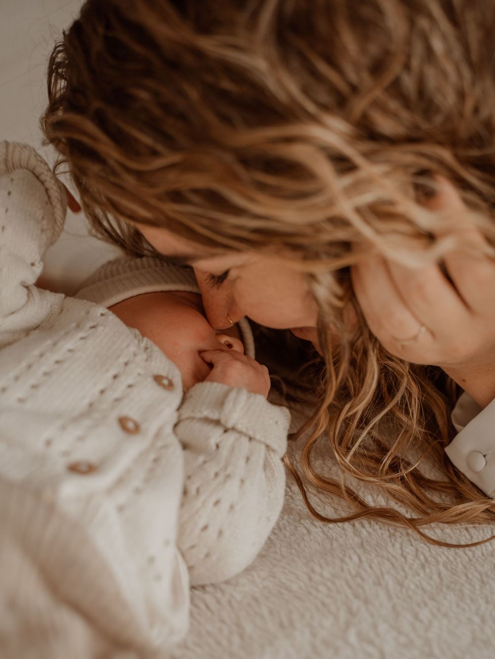 Intimate moment captured between parent and newborn in soft, warm lighting.