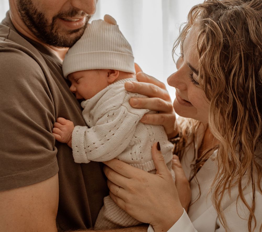 A tender family moment captured in warm tones showing parents cradling their newborn baby in a series of intimate shots.