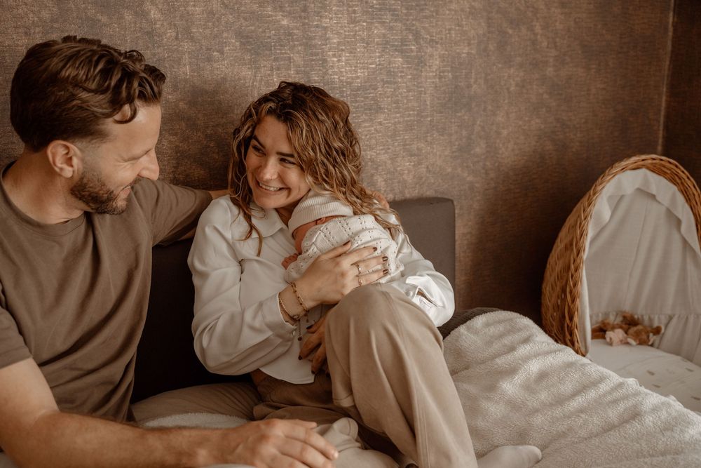 Warm-toned lifestyle photos of parents sharing tender moments with their newborn baby.