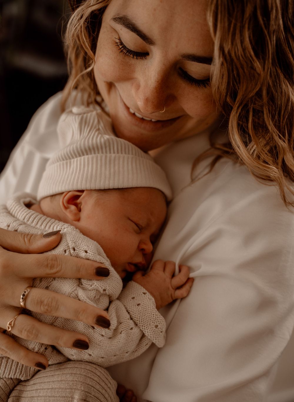 Gentle moments between parent and newborn captured in warm, muted tones.