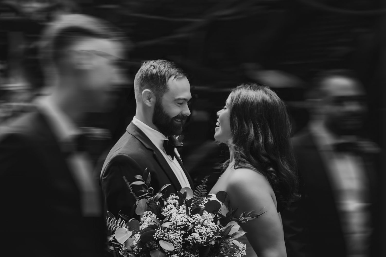 A tender black and white wedding moment captured between two people as they share an intimate gaze holding a bouquet.