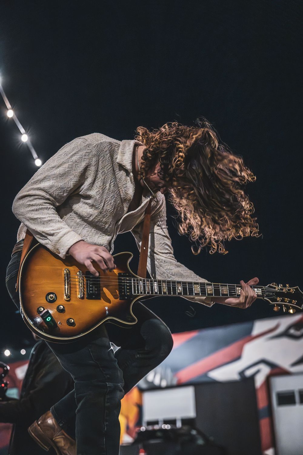 Musician performing with a vintage Gibson Les Paul guitar on stage in dramatic lighting.
