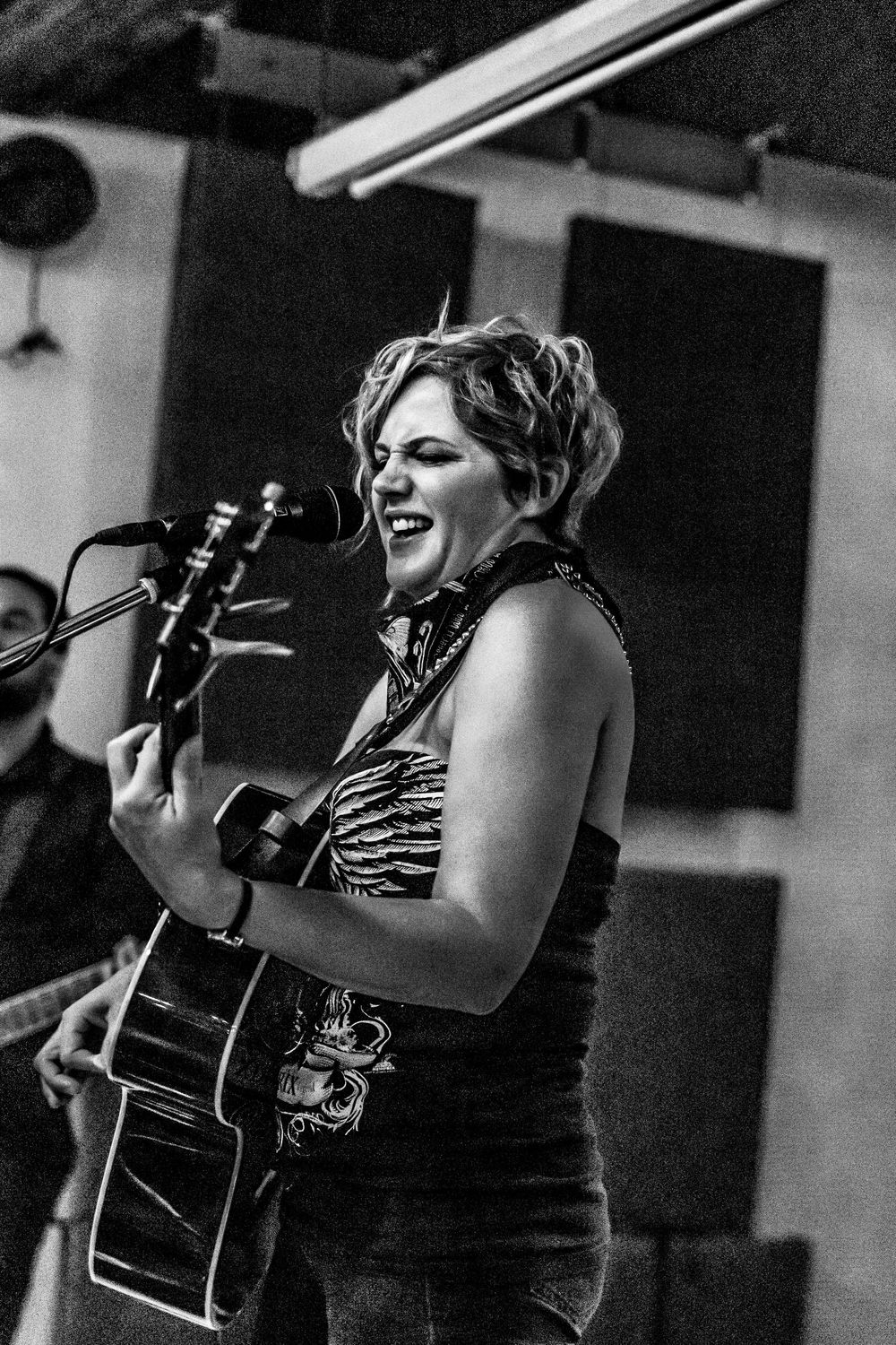Black and white photo of acoustic guitar performance on stage.