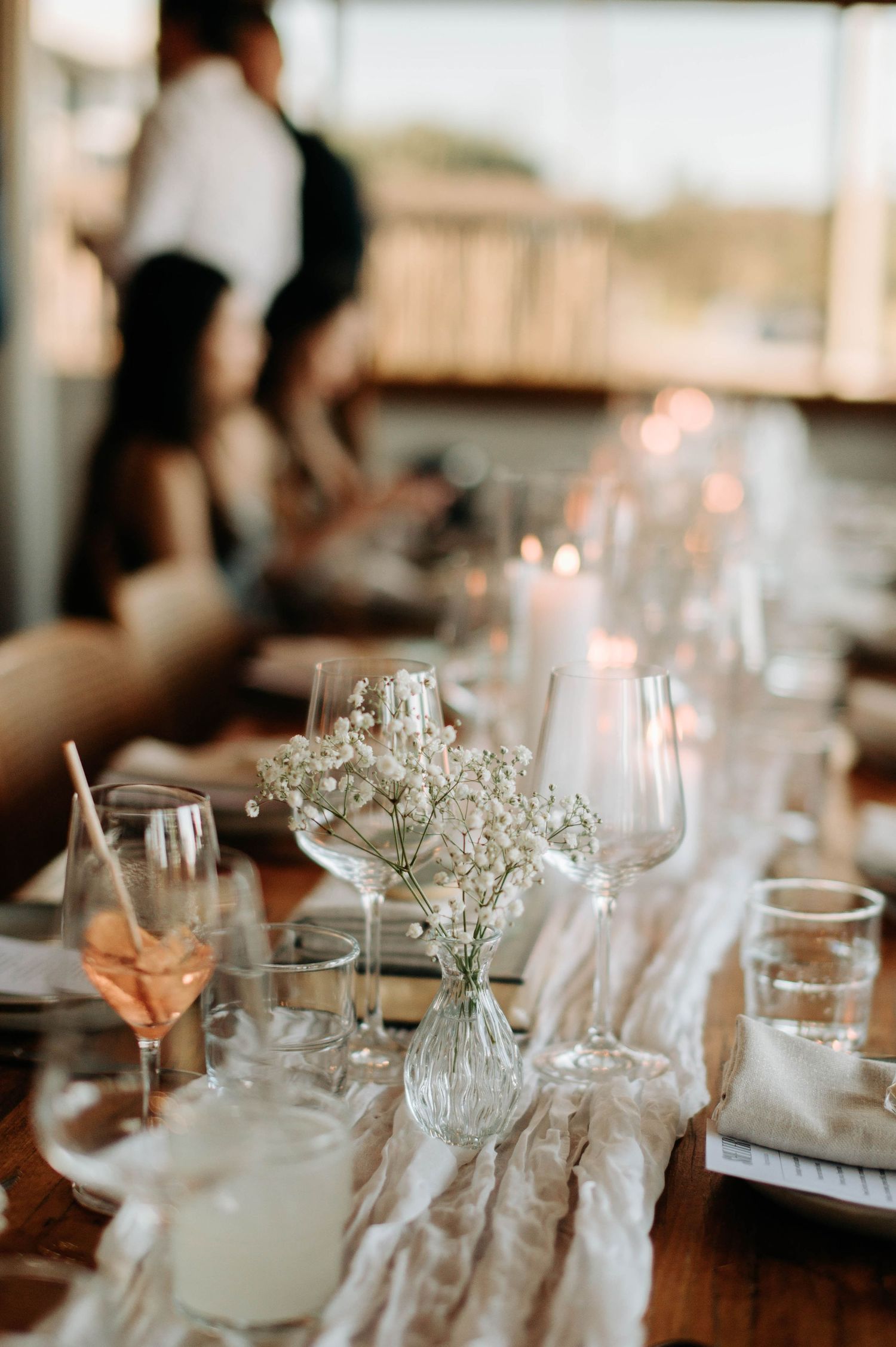 Intimate wedding reception table setting with wine glasses and delicate floral centerpieces.
