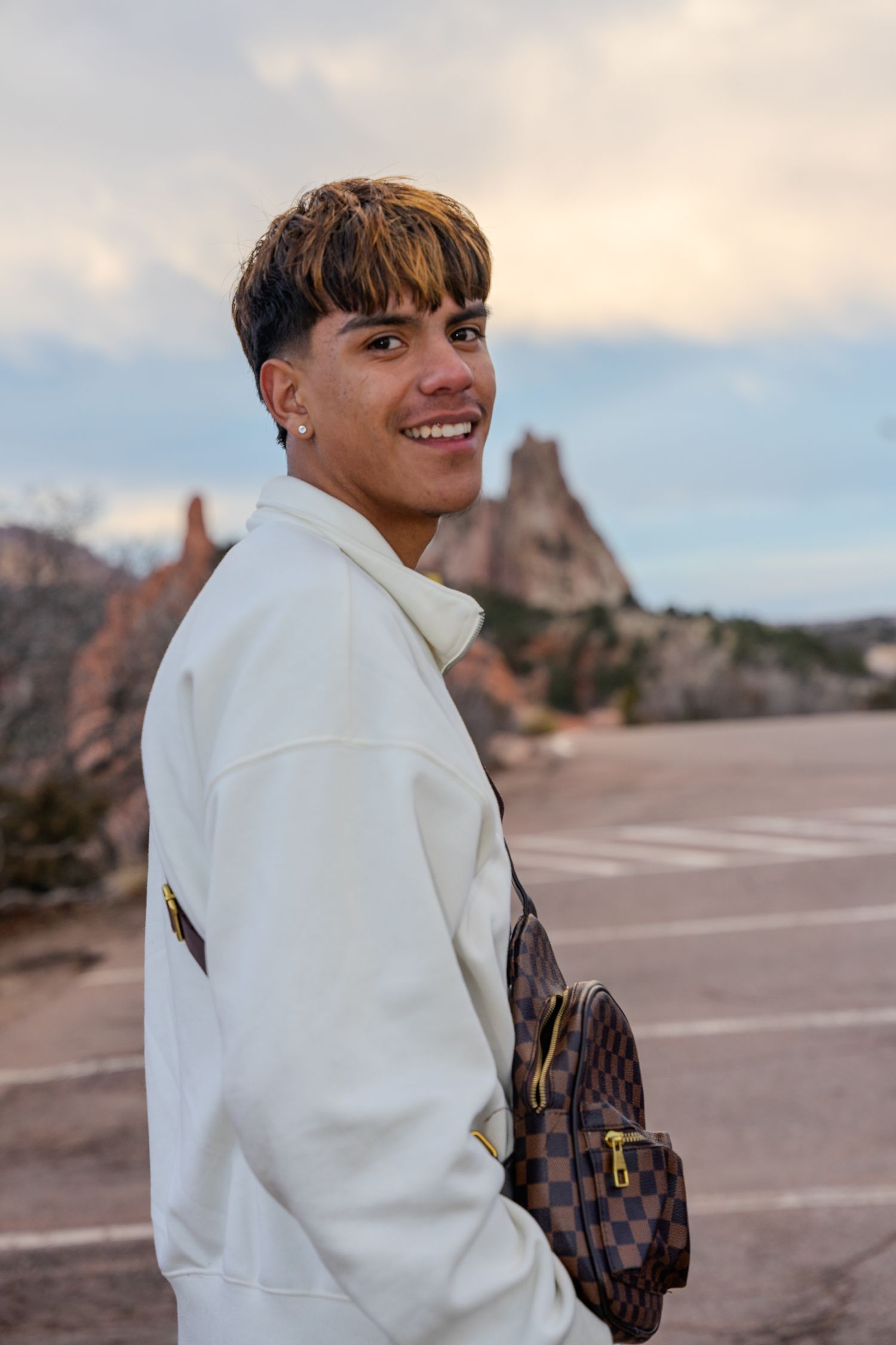 Person in white sweater smiling against desert mountain backdrop.