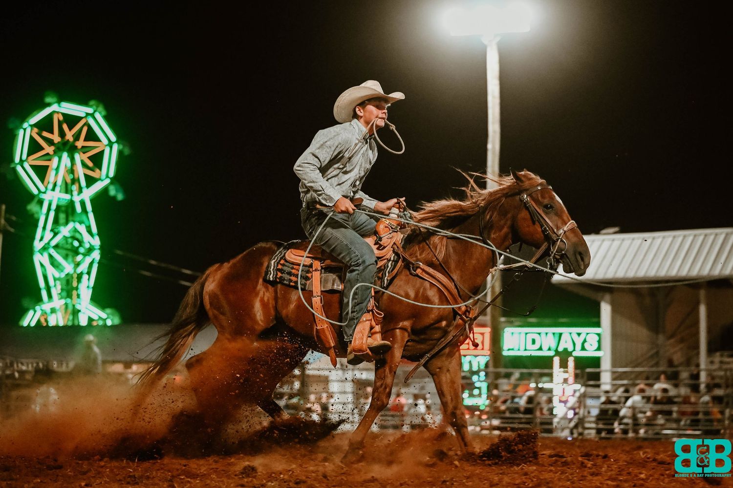 Nighttime rodeo scene with neon lights and cowboys competing in the arena.