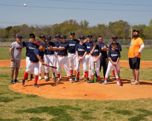 Youth baseball team in navy blue uniforms gathers on pitching mound for a fun and silly team picture.