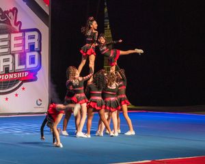 Cheerleaders in red and black uniforms perform a pyramid stunt at the Cheer World Championship competition.