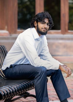 Professional portrait of a teen in business casual attire sitting casually on a wooden bench outdoors for minneapolis senior photography