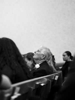 The father of the woman tilts his head back, eyes closed, listening to the music at his daughter's funeral