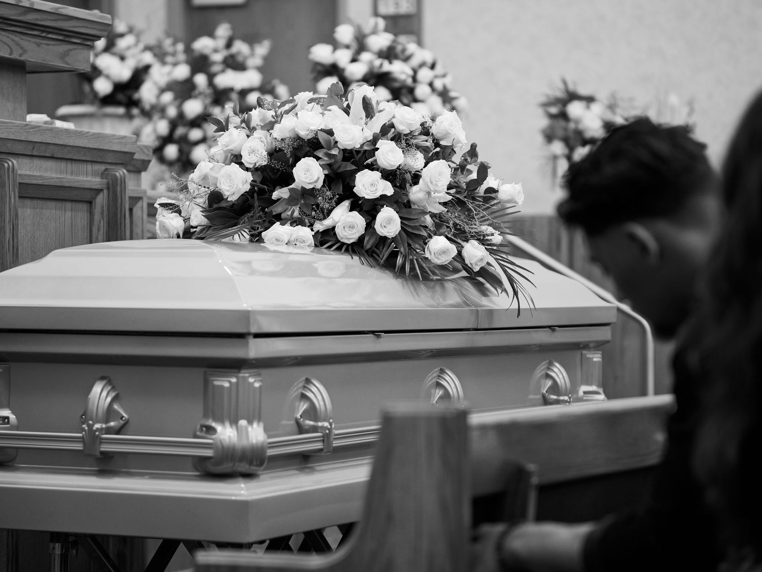 a beautiful arrangement of flowers sit atop the casket in a chapel.