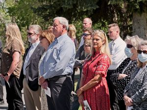 A group of people stand looking on at the graveside