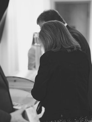 A man and woman stand in front of the open casket of a loved one, giving their final farewells