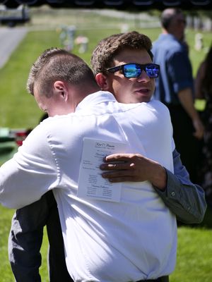 Two young men embrace in support at a funeral