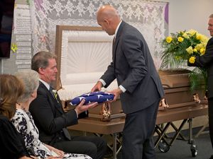 An officiant hands the folded American flag to a son of the deceased.