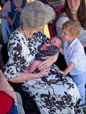 A great grandmother holds her newest great grandchild at the funeral of her late husband.