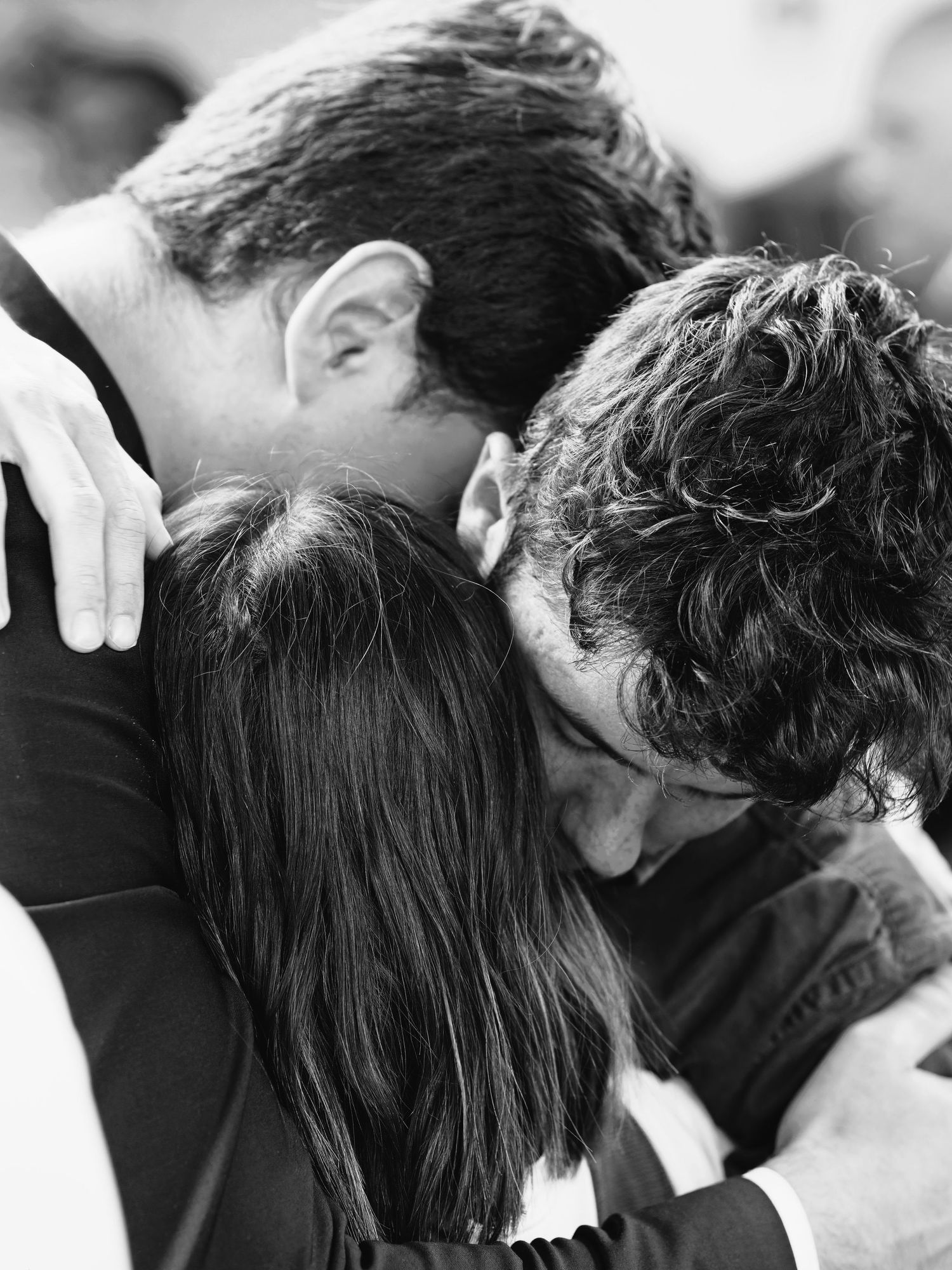Three friends hug tightly at a funeral