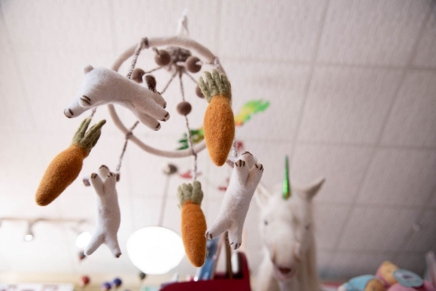 Multiple gray cats playfully leap and jump to catch suspended carrot toys as a white bunny watches in the background.