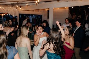 Guests dancing and celebrating at a lively indoor wedding reception with string lights.