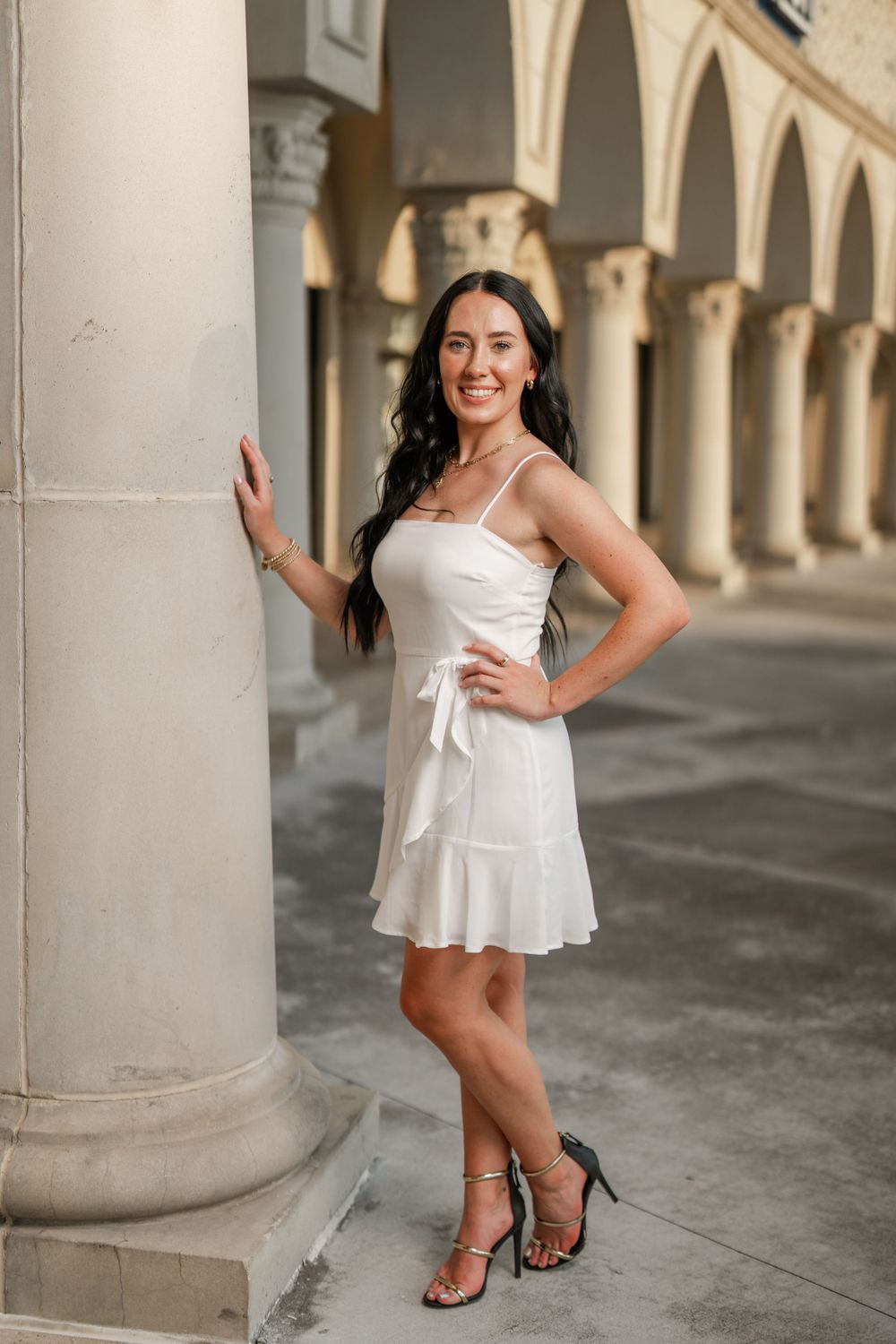 White sundress photoshoot with classic architecture and stone columns in the background.