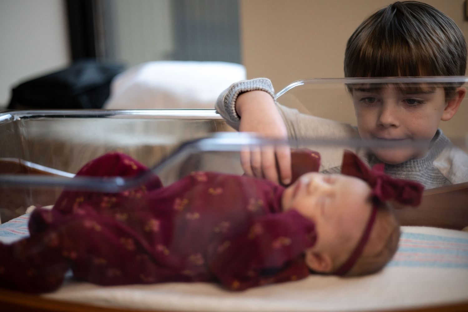 Central Illinois photographer captures a boy playing with a newborn during a Fresh 48 newborn photo session in Springfield, IL