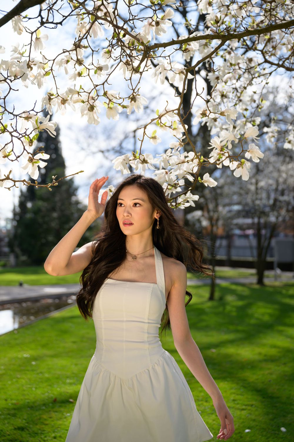 Minimalist fashion portrait outdoors in Zurich. Model with flowing hair, clean white styling and glowing skin