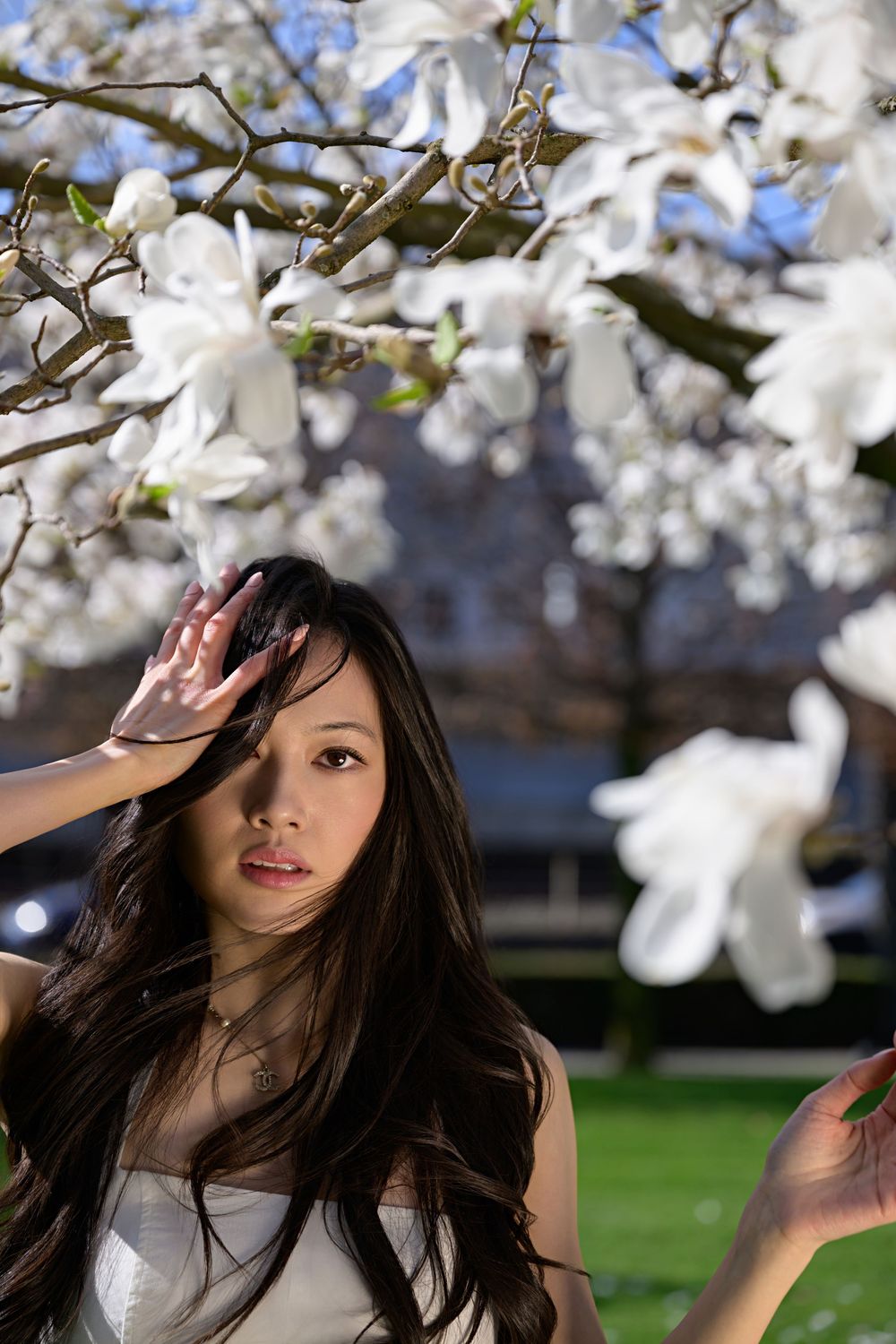 Outdoor fashion Zurich – model under spring blossoms, white outfit, minimal styling, clean beauty.
