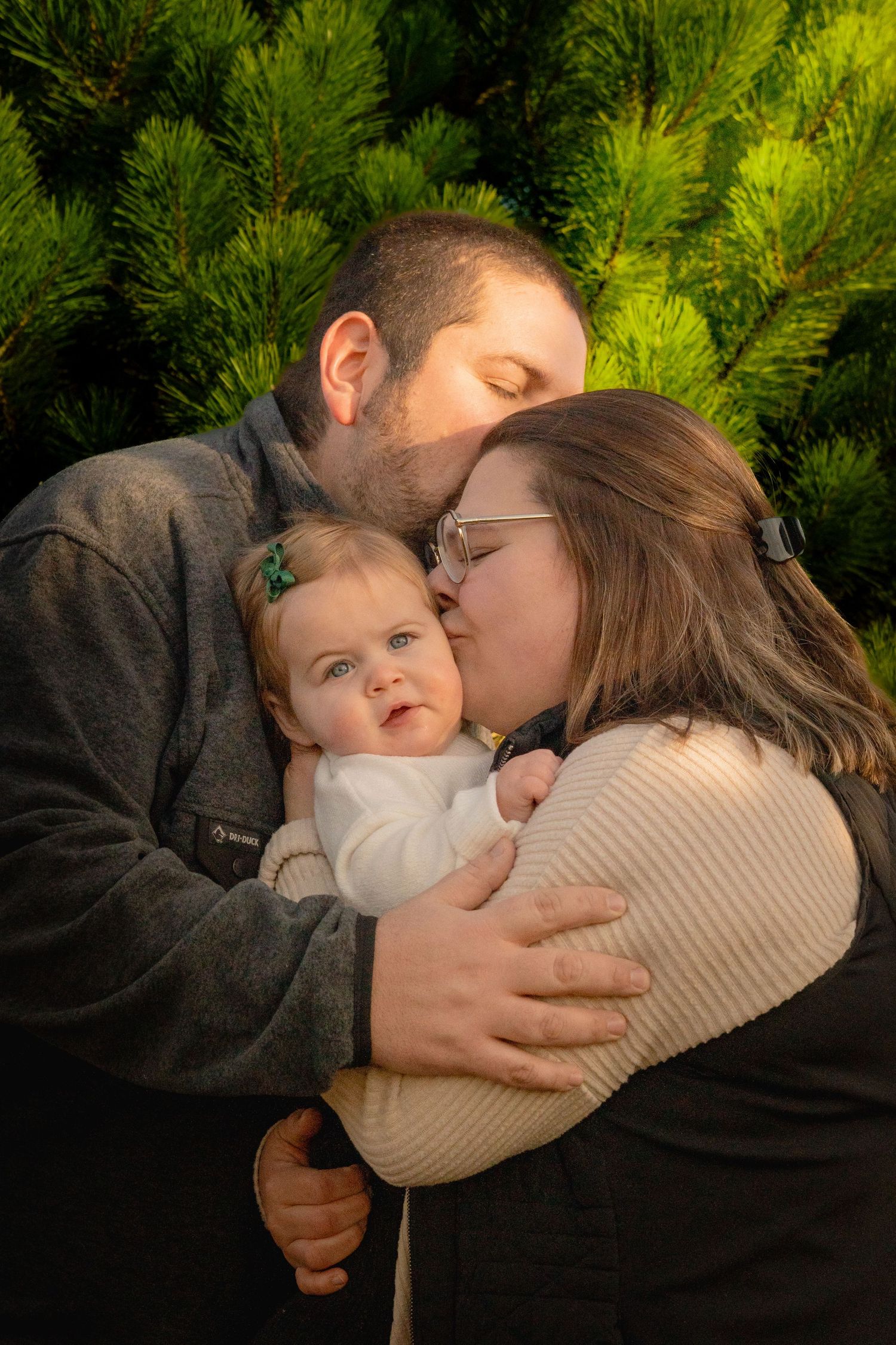 A tender family moment captured in a series of photos with evergreen trees in the background.