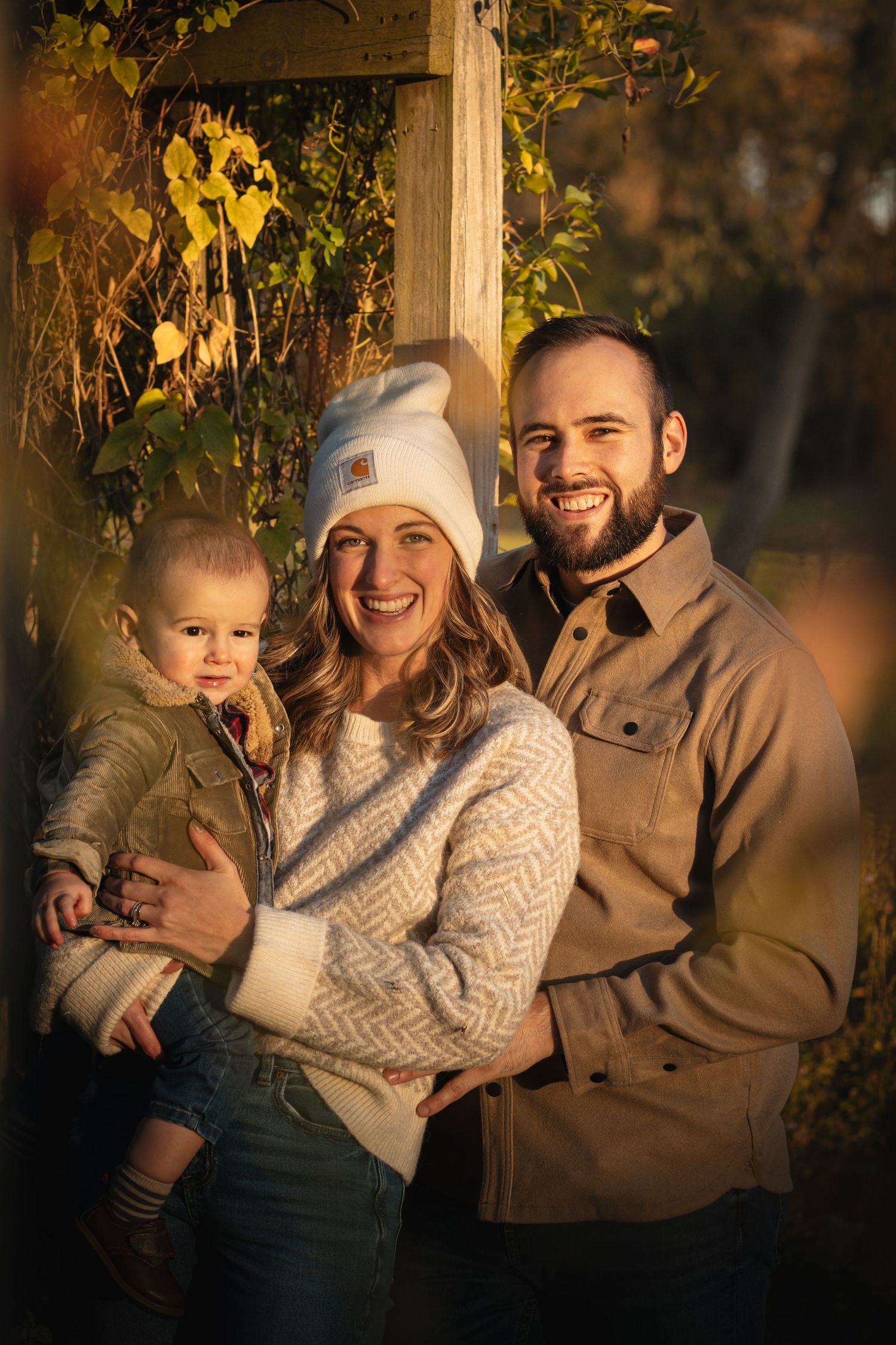 a beautiful family standing under a terrace, the sun shining and highlighting them. beautifully exposure in in this fall family photo.
