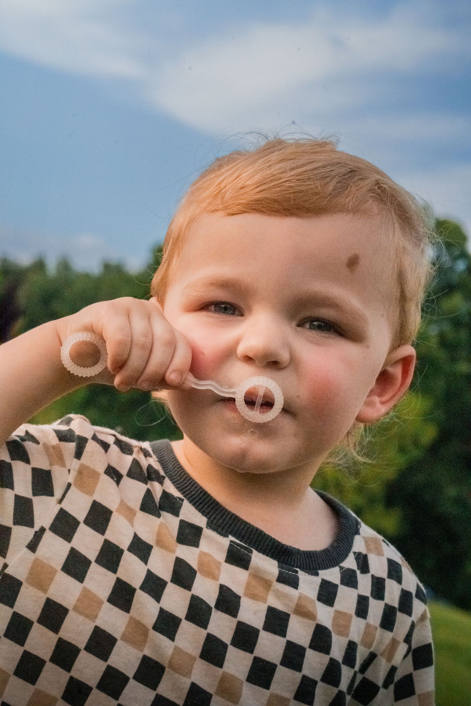 A playful portrait series outdoors showing a checkered shirt and upturned nose poses in natural lighting.
