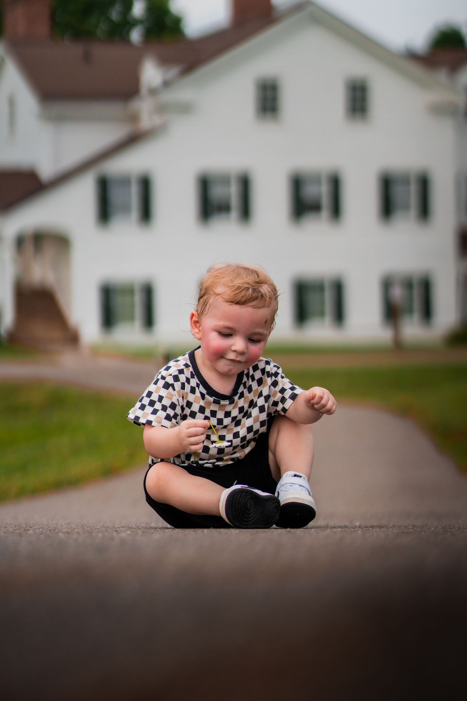 A sequence of images showing a crawling toddler on pavement with a white farmhouse building in the background.