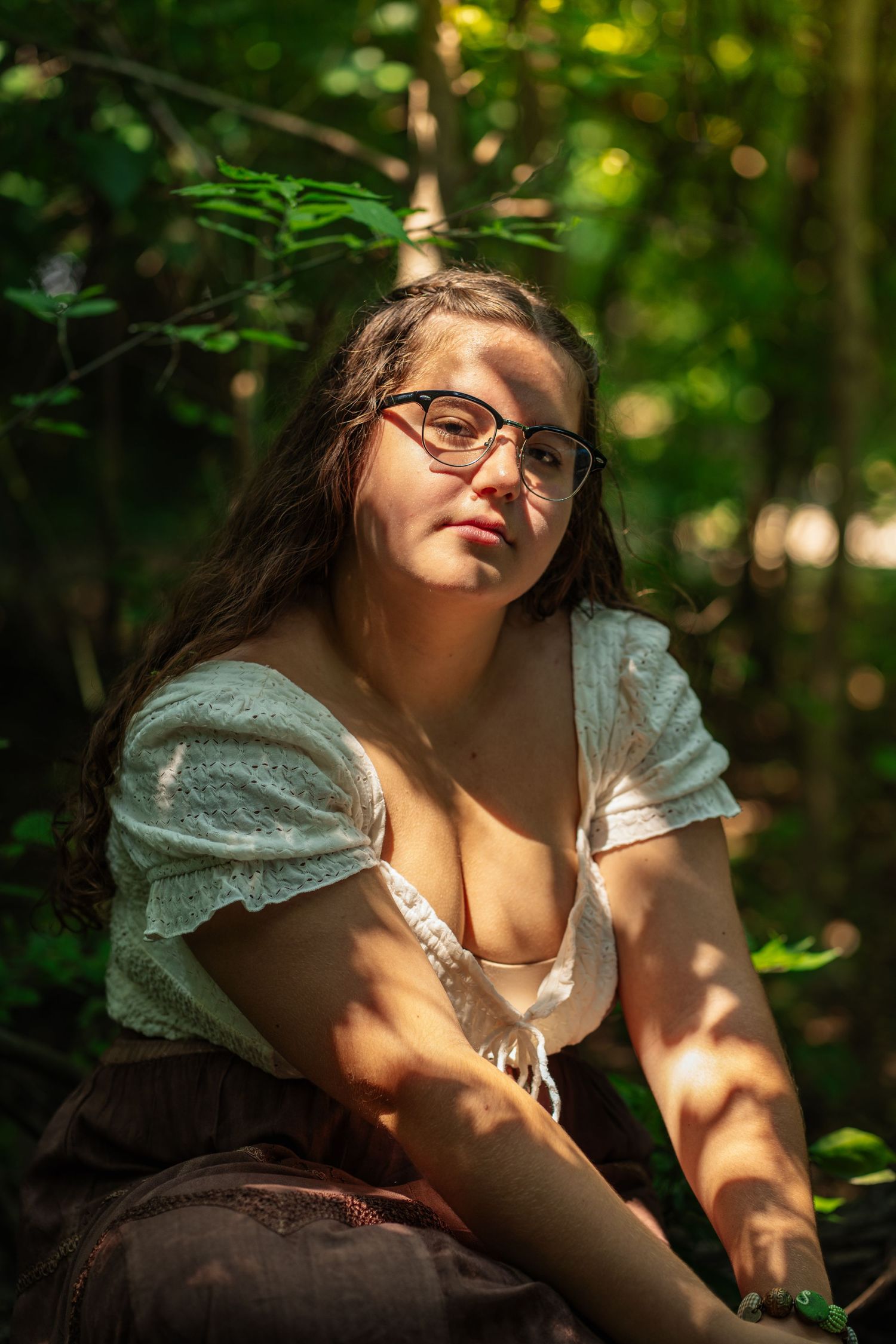 Sunlight dapples through trees onto a person relaxing in a woodland setting with a dreamy expression.