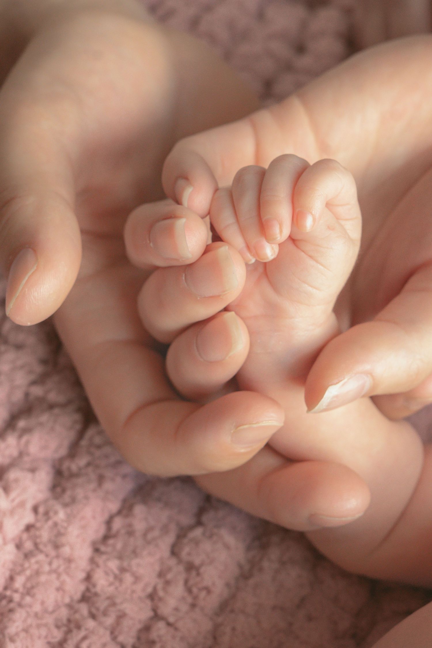 Close-up sequence of tiny newborn baby feet showing delicate toes against a soft pink textured background.