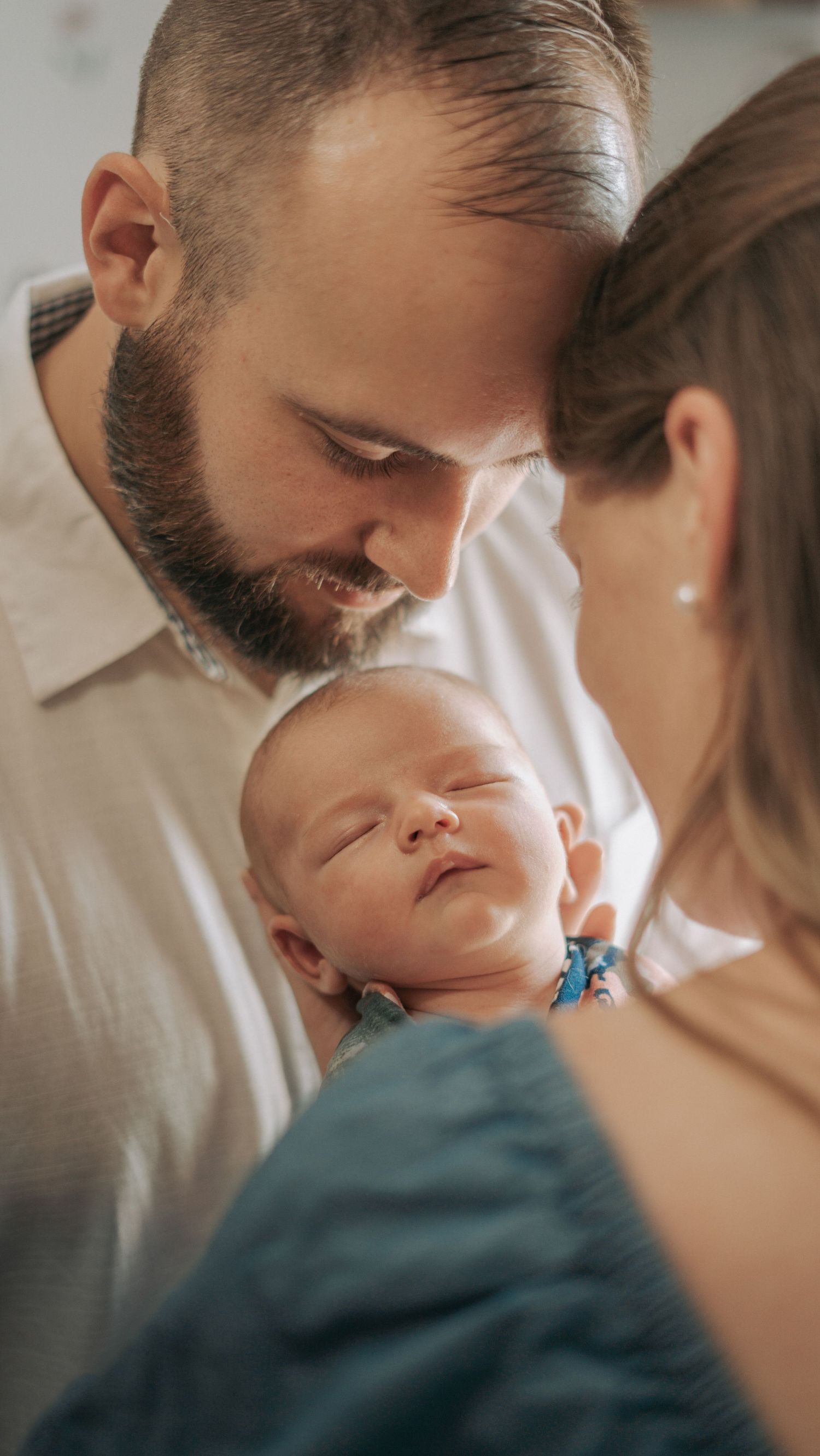 A tender moment is shared between parent and sleeping baby in a series of intimate close-up photographs.