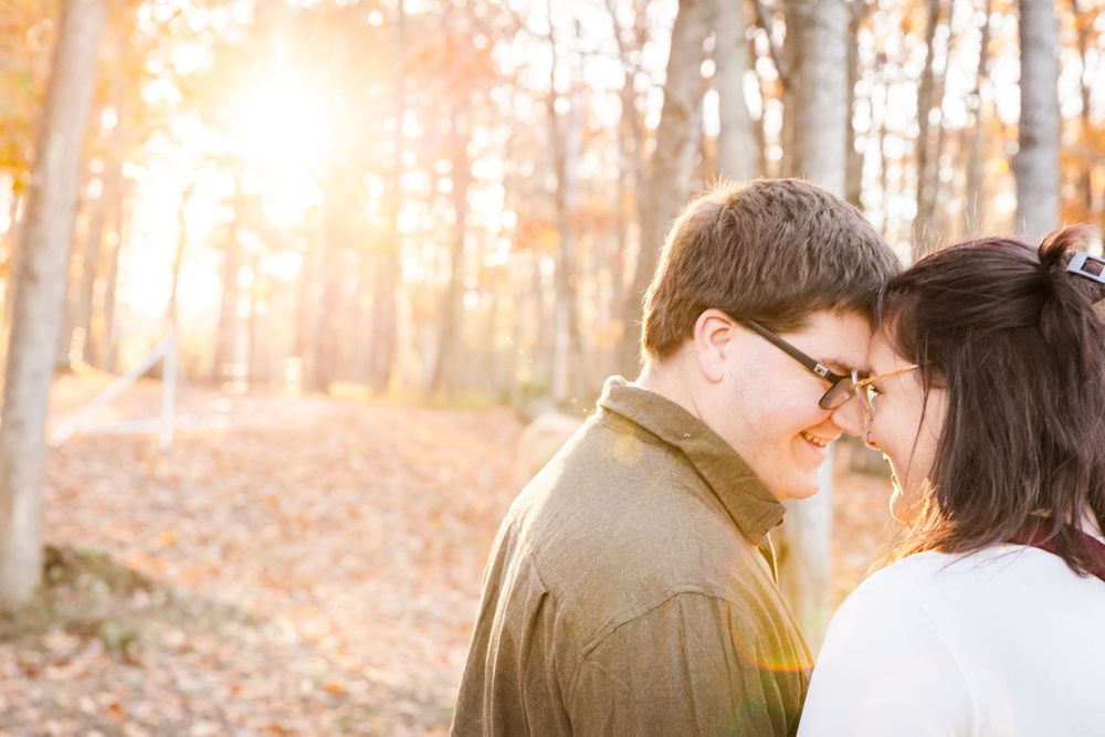 A tender moment between a couple in a sunlit autumn forest with golden leaves.