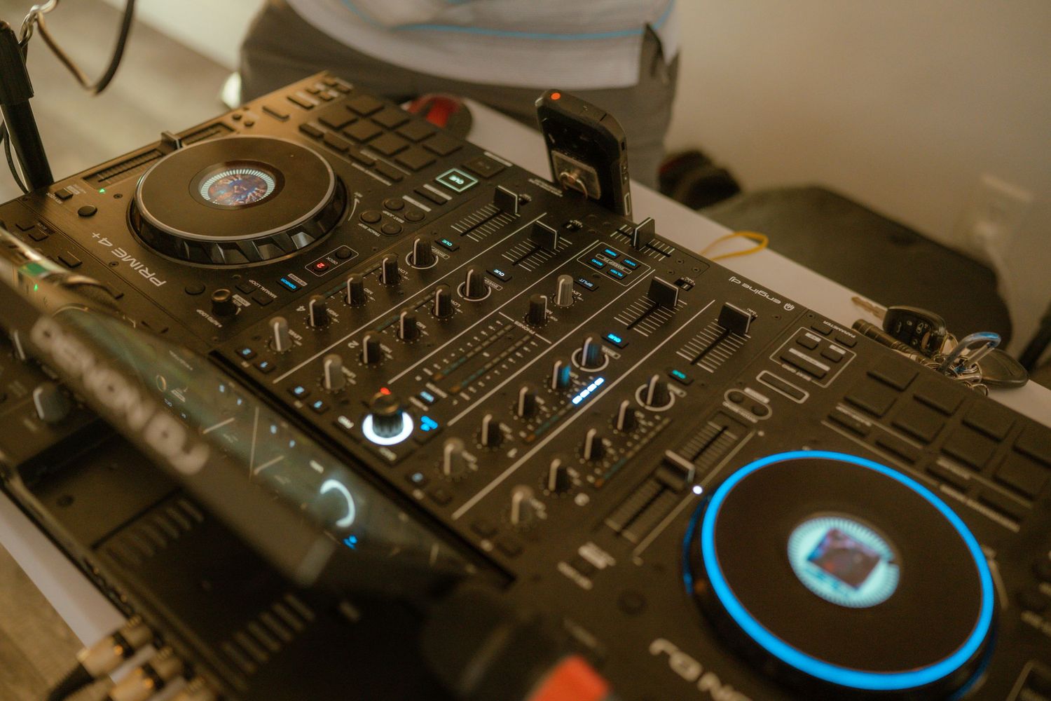 Professional DJ mixer equipment with blue backlit controls and knobs on black surface.