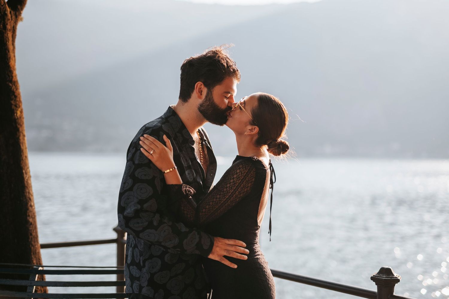 Giovane coppia di fidanzati si scambia un bacio con lo sfondo delle acque del lago.