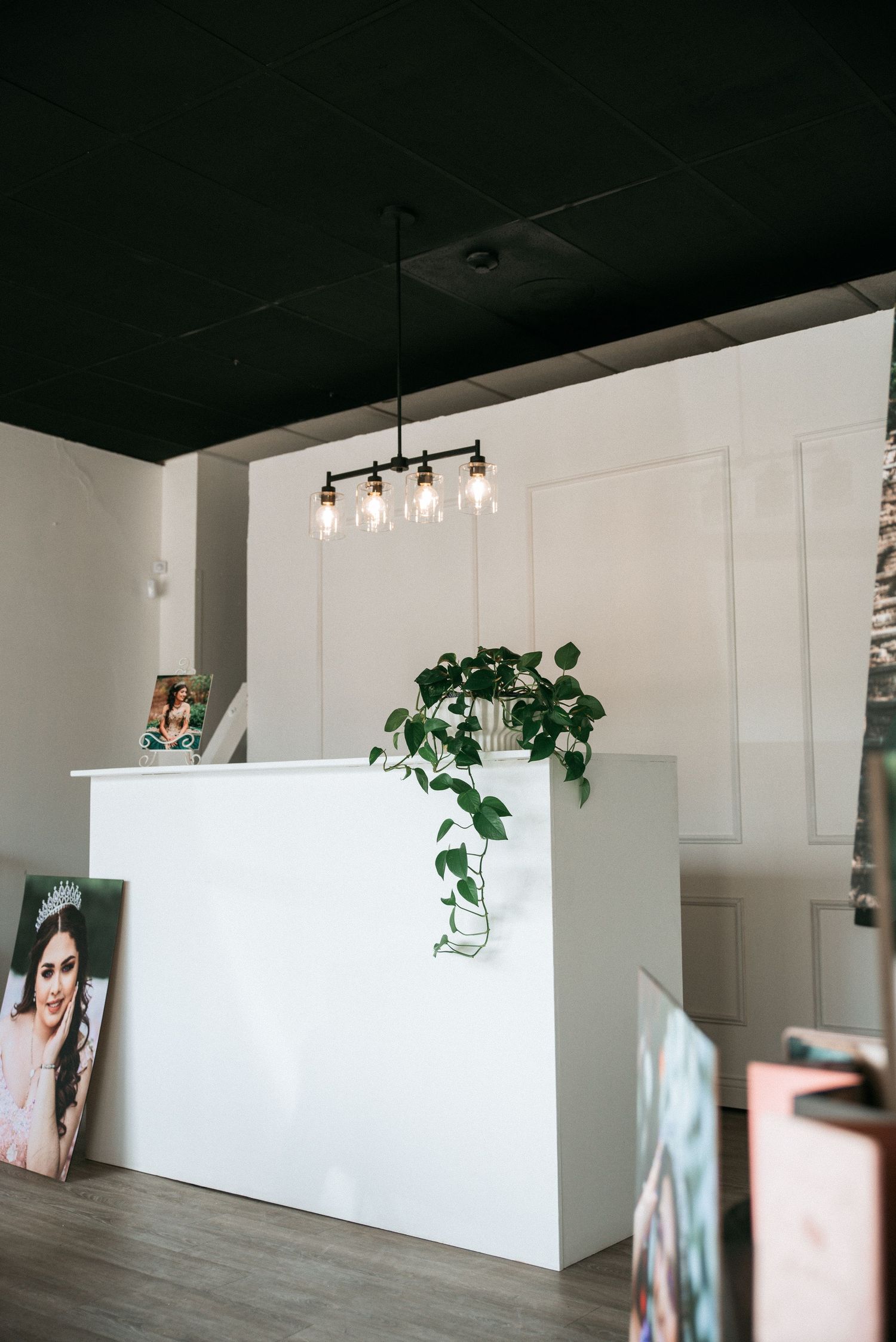 Modern photography studio reception area with white walls, black ceiling and hanging pendant lights.