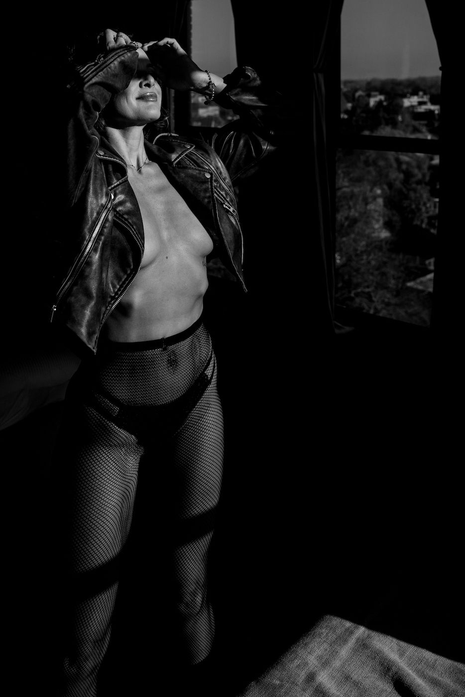 A black and white photo shows a figure in Calvin Klein underwear lounging on white bedding with dramatic lighting.