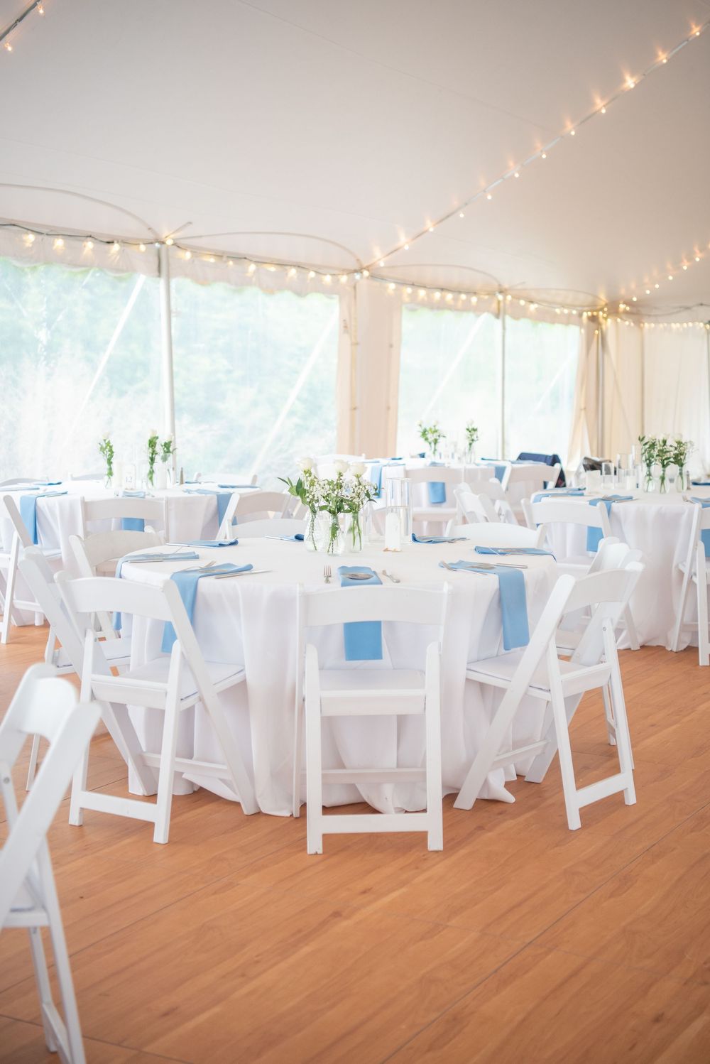 Elegant wedding reception setup with white chairs and string lights.