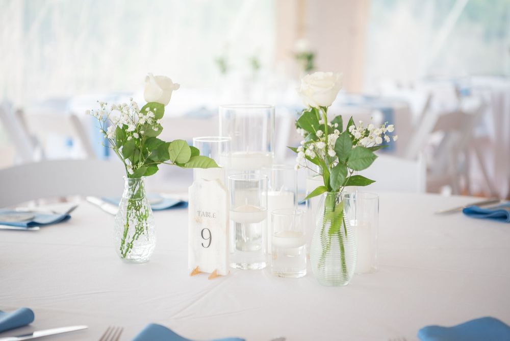 Wedding reception tables with white linens and blue napkin accents.